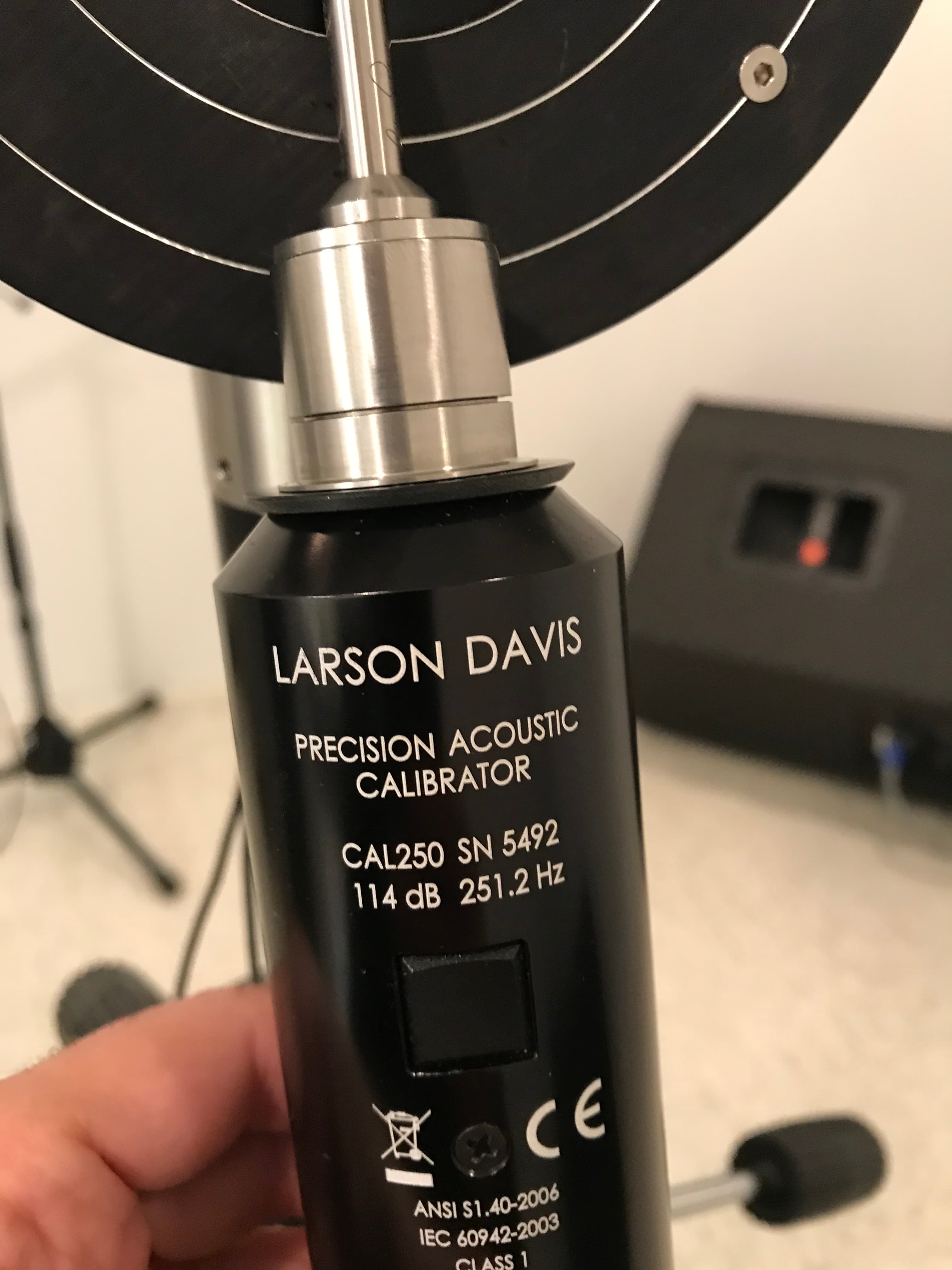 A measurement microphone mounted in a laboratory test fixture for calibration.