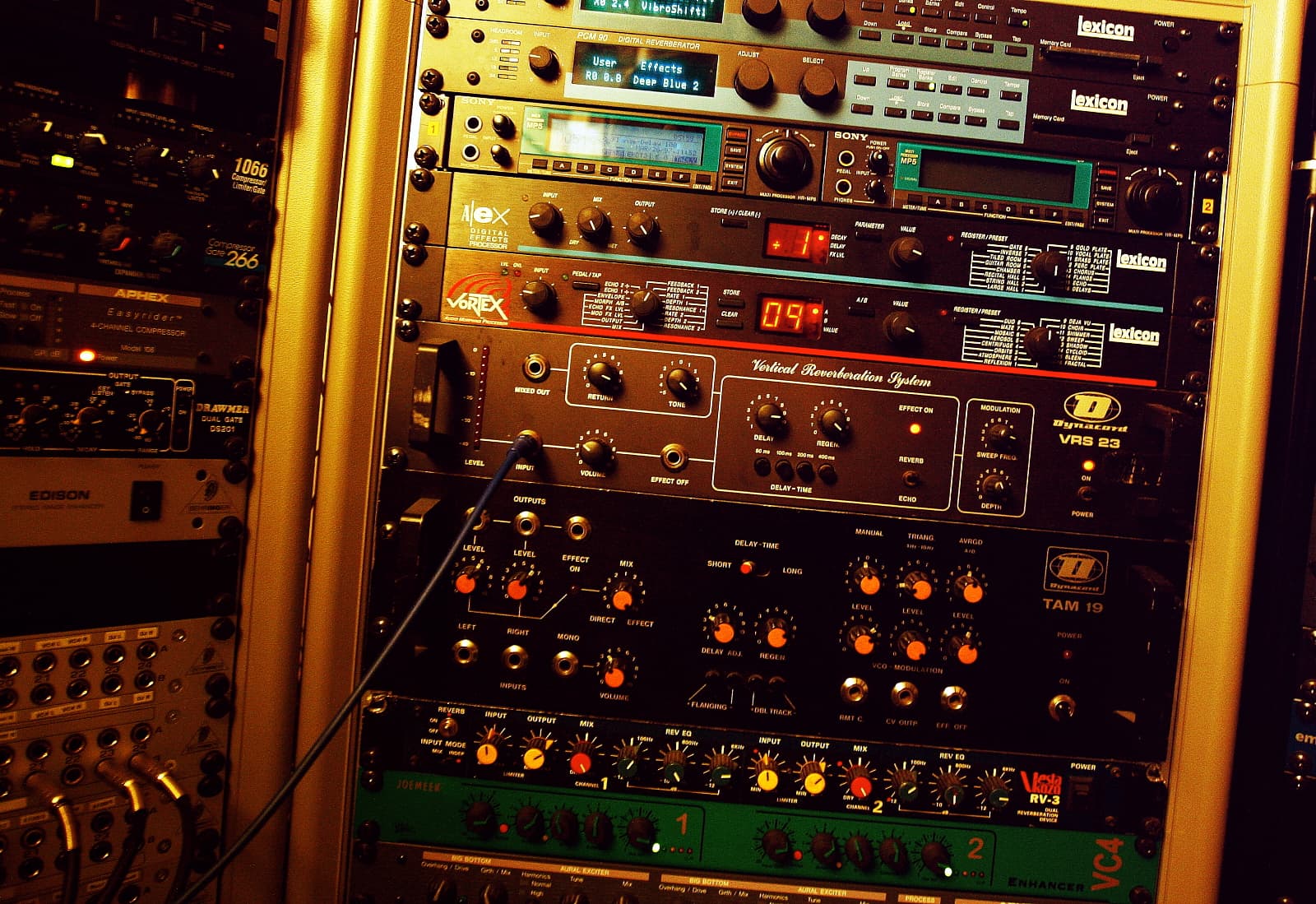 A rack of outboard studio processors with front-panel controls and metering.