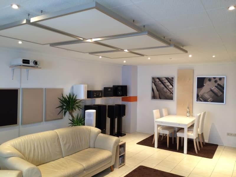 A domestic listening room with absorber panels on the walls and a suspended array of panels on the ceiling above the seating area.