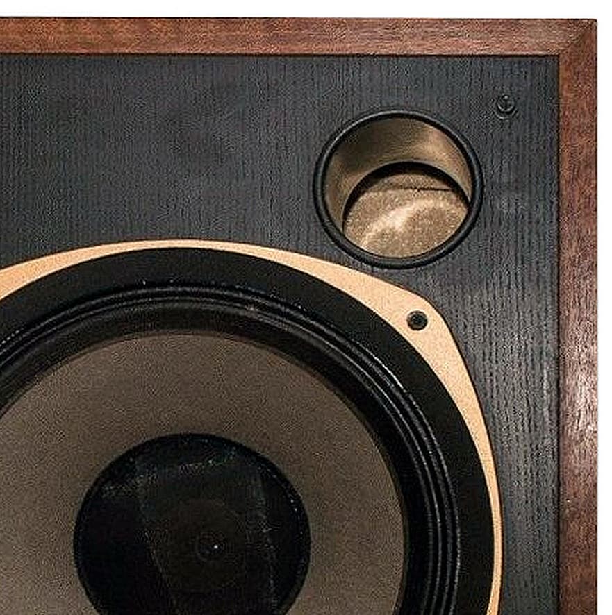 Close-up of a round bass reflex port in the front baffle of a studio monitor, above the edge of the woofer.