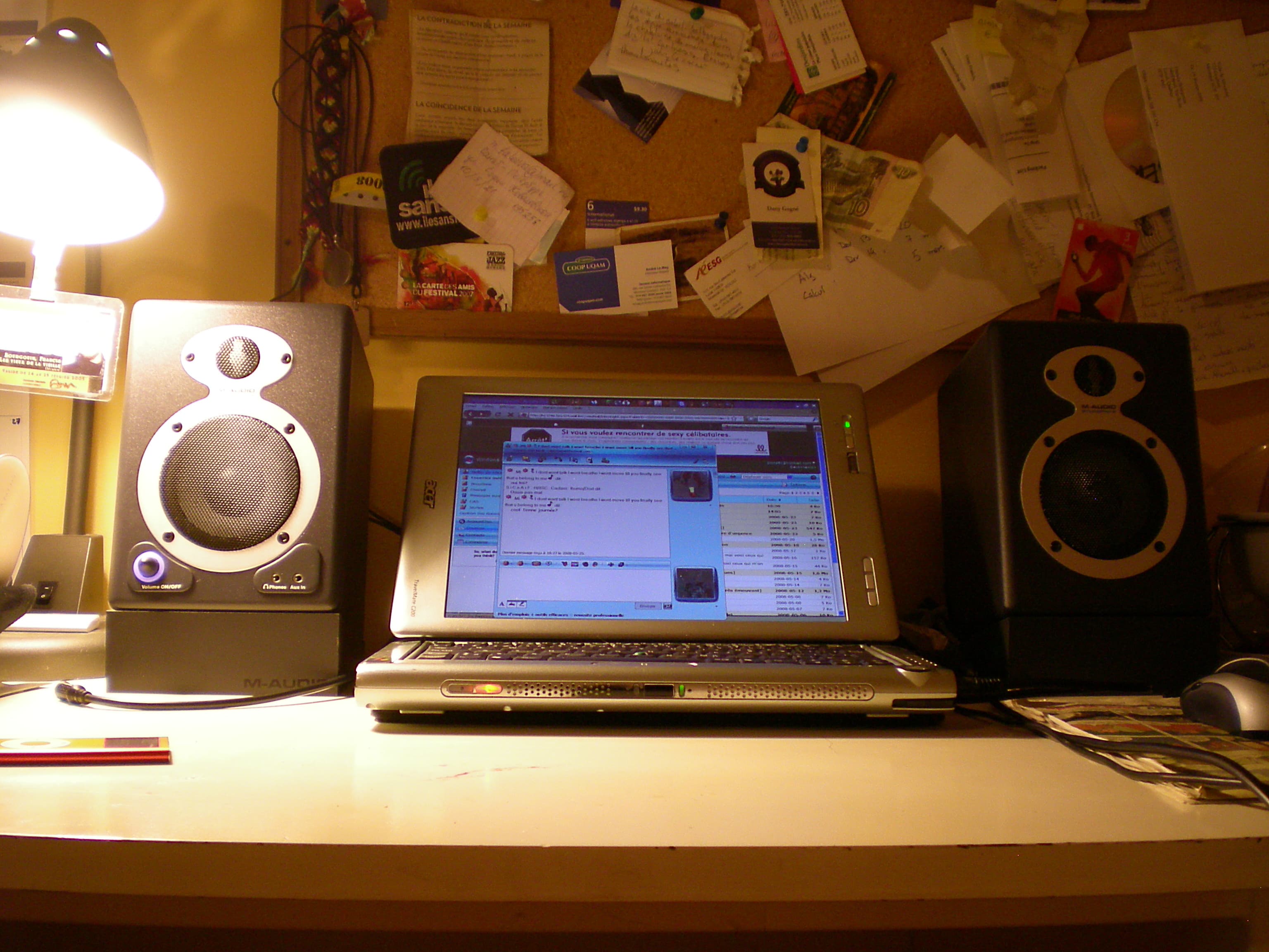 A pair of compact studio monitors raised on angled desktop stands beside a laptop.